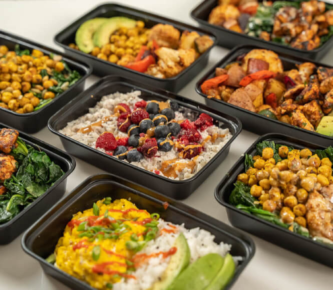 A set of neatly organized meal prep containers arranged on a countertop, each filled with balanced, pre-portioned meals ready to enjoy.