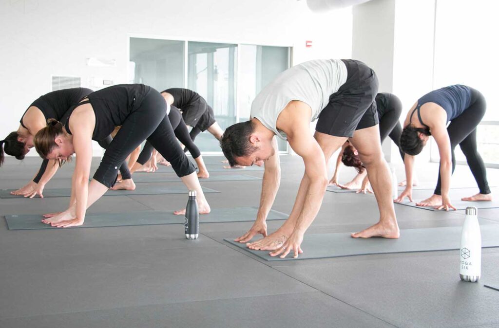 People participating in a guided mobility and stretch session in a fitness studio, performing various stretches on yoga mats with a focus on flexibility and joint movement. The environment is calm and supportive, emphasizing body alignment and range of motion.