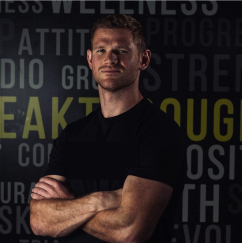 "Trainer in gym gear standing confidently in front of studio background"