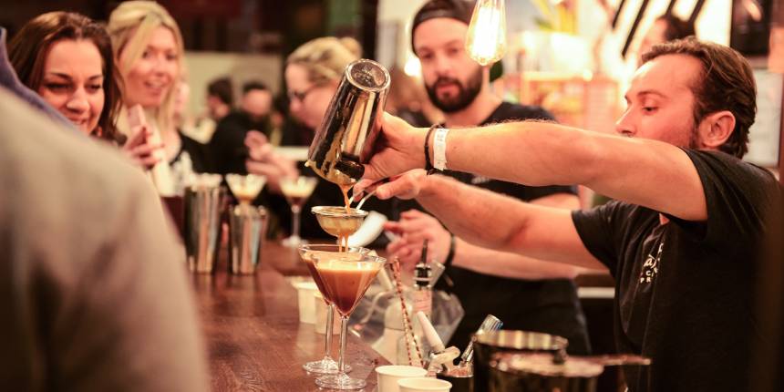 Participants engaged in a hands-on cocktail making class, mixing fresh ingredients and garnishing drinks in a lively group setting.